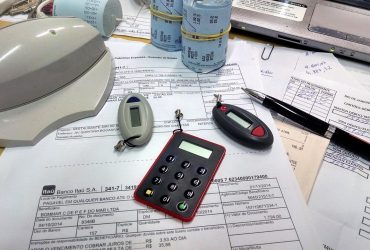 O que é Split Payment e como ele vai mudar o jeito de pagar impostos no Brasil Mesa com boletos, calculadora e comprovantes de máquina de cartão ilustrando como o Split Payment vai mudar o pagamento de impostos no Brasil