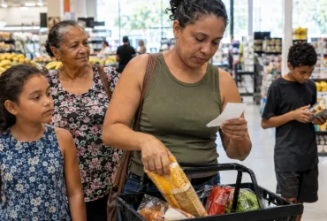 Família brasileira em supermercado ilustrando como funciona o cashback do IBS e da CBS para inscritos no CadÚnico