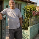 Morador em frente à casa simples que ocupa há anos e pretende regularizar por usucapião